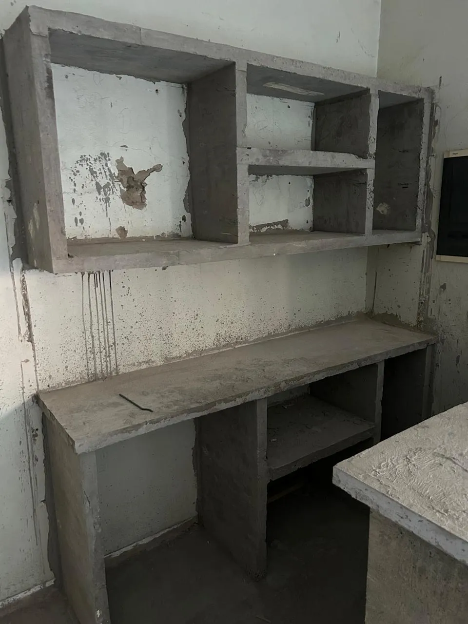 Bar area with bare, stained cement shelving and counters