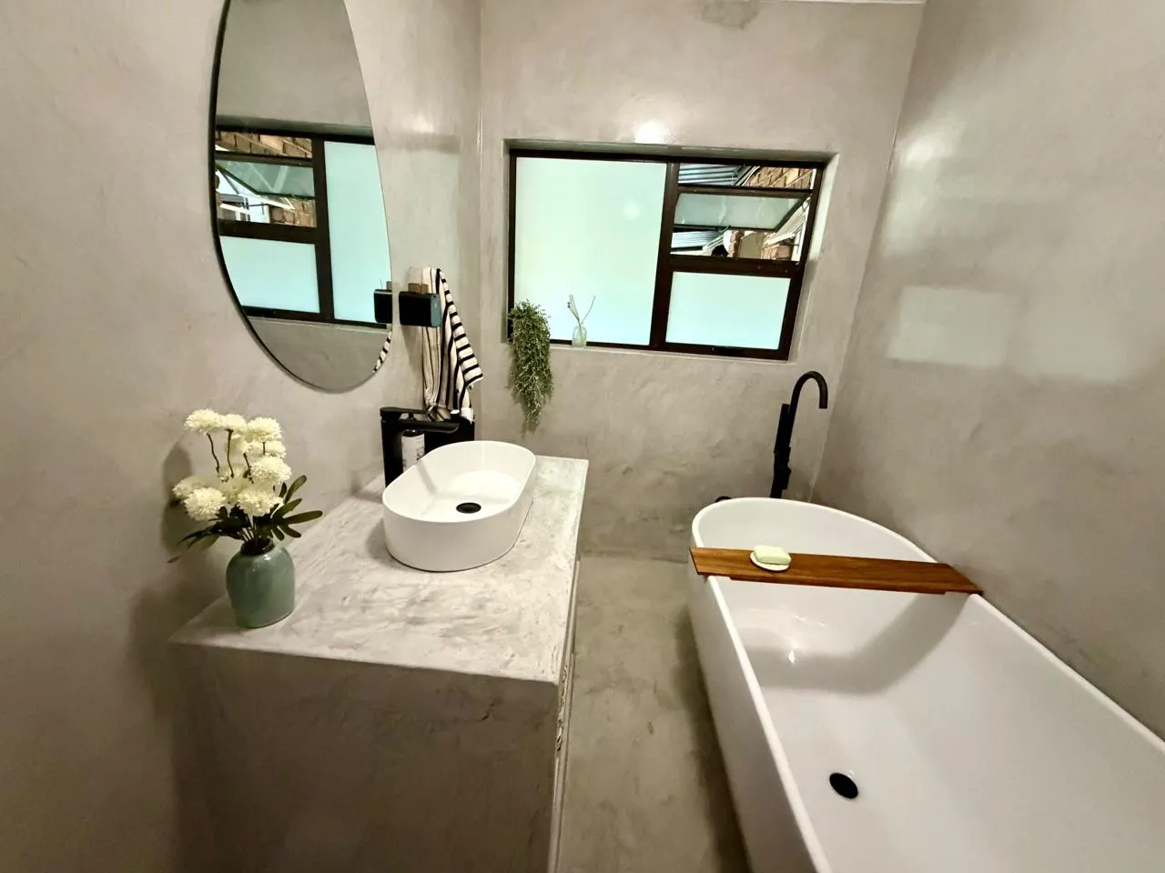 Bathroom finished in decorative cement: walls, vanity and floor, with a freestanding bath